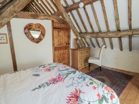 A bedroom with floral bedding wooden beams a wooden door a chest of drawers a chair and a mirror at Old Ty'n Y Wern in Rhosygwalia near Bala
