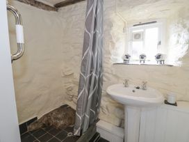 A bathroom with a shower area with curtain a white pedestal sink three decorative sheep on the window ledge at Old Ty'n Y Wern in Rhosygwalia near Bala