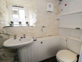 A bathroom with a sink a toilet a small window with decorative sheep figures and shelves at Old Ty'n Y Wern in Rhosygwalia near Bala