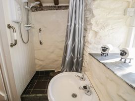 A bathroom with a shower area and a sink with two taps at Old Ty'n Y Wern in Rhosygwalia near Bala