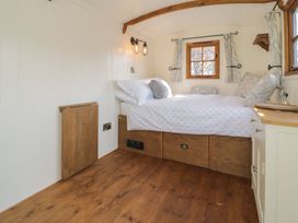 A small bedroom with a bed beside two windows and a wooden floor at Old Ty'n Y Wern in Rhosygwalia near Bala