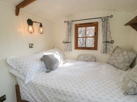 A bedroom with a bed next to a window with curtains and wall-mounted lights at Old Ty'n Y Wern in Rhosygwalia near Bala