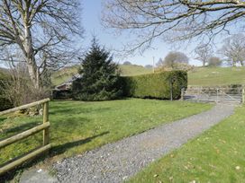 A grassy yard with a gravel path leading to a metal gate and trimmed hedges at Old Ty'n Y Wern in Rhosygwalia near Bala