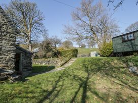 A grassy garden area with stone steps a wooden railing a stone building and a green shed at Old Ty'n Y Wern in Rhosygwalia near Bala