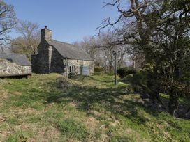 Stone cottage in grassy yard with trees and lamppost at Old Ty'n Y Wern in Rhosygwalia near Bala