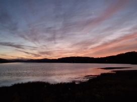 A body of water with hills in the background under a cloudy sky at sunset at Old Ty'n Y Wern in Rhosygwalia near Bala