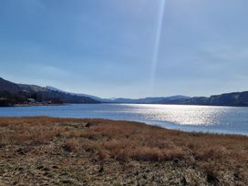 A lake with grassy shore and hills in the background at Old Ty'n Y Wern in Rhosygwalia near Bala