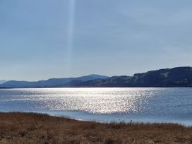 A lake with sunlight reflecting on the water and hills in the background at Old Ty'n Y Wern in Rhosygwalia near Bala