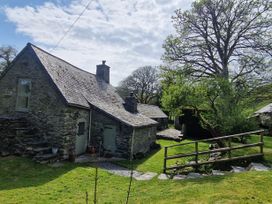 A stone cottage with a slate roof and green doors surrounded by grass and trees at Old Ty'n Y Wern in Rhosygwalia near Bala