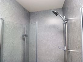A shower area with glass partitions and showerhead at Havelock Hideaway in Windermere