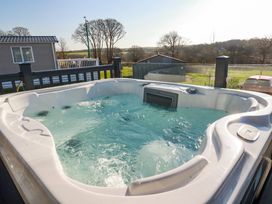 An outdoor hot tub on a deck with a railing and countryside view at The Maples No 48 Hewas Water near Sticker