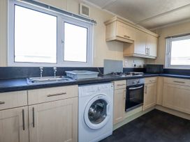 A kitchen with a washing machine and oven at Lazy Days in St Merryn