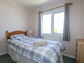 A bedroom with a bed, lamp, and window at Lazy Days in St Merryn