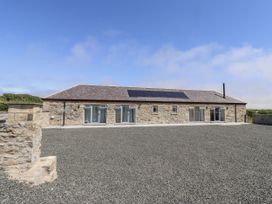 A stone house with gravel area and solar panels at West Burton Hemmel in Bamburgh