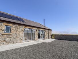 An exterior view of a stone house with solar panels at West Burton Hemmel in Bamburgh