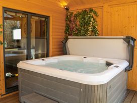 A wooden room with a hot tub and a sliding glass door showing a kitchen at Alpaca Lodge in Barkston