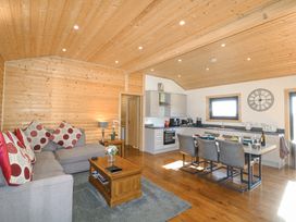 An open living room and kitchen with wooden walls and ceiling at Alpaca Lodge in Barkston