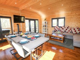 A dining area with a table set for six and a living room with a sofa and coffee table in a wooden cabin at Alpaca Lodge in Barkston