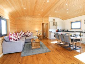 An open plan living area with a gray sofa, wooden coffee table, dining table with six chairs, and a kitchen at Alpaca Lodge in Barkston