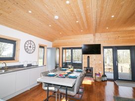 A kitchen dining area with a table set for six a wood stove a television and glass doors at Alpaca Lodge in Barkston