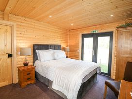 A bedroom with a bed bedside tables lamps a wardrobe and glass doors at Alpaca Lodge in Barkston