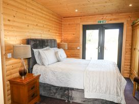 A bedroom with a bed lamps a wooden wardrobe and glass doors at Alpaca Lodge in Barkston