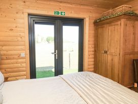 A bedroom with a bed a wooden wardrobe and glass doors with a fire exit sign at Alpaca Lodge in Barkston