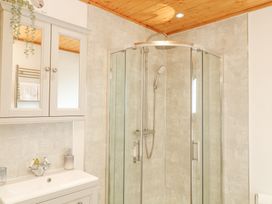 A bathroom with a glass shower enclosure a sink with a cabinet and a mirrored medicine cabinet at Alpaca Lodge in Barkston