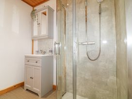 A bathroom with a shower enclosure and a sink cabinet with a mirrored wall cabinet above at Alpaca Lodge in Barkston
