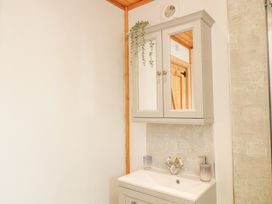 A bathroom sink with a cabinet mirror and soap dispenser at Alpaca Lodge in Barkston