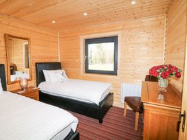 A bedroom with two single beds a wooden dresser with flowers and a window at Alpaca Lodge in Barkston