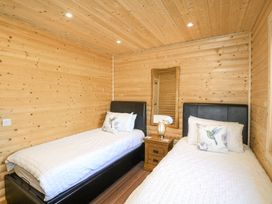A bedroom with two single beds a wooden nightstand with a lamp and a wall mirror at Alpaca Lodge in Barkston