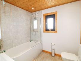 A bathroom with a bathtub shower combination window and toilet at Alpaca Lodge in Barkston