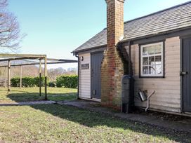 The exterior of a wooden building with a chimney a water butt and a pergola structure at The Woodshed in Tendring near Weeley