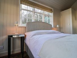A bedroom with a bed between two bedside tables with lamps and a window behind the bed at The Woodshed in Tendring near Weeley