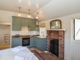 A kitchen with green cabinets a brick fireplace and folded towels on a table at The Woodshed in Tendring near Weeley