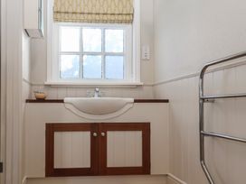 A bathroom sink with wooden cabinet below a window with patterned glass and a chrome towel rail on the right at The Woodshed in Tendring near Weeley