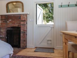 An interior room with a half open wooden door a brick fireplace and a wooden table with a chair at The Woodshed in Tendring near Weeley