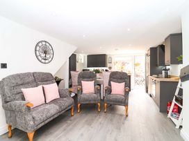 A living room with sofa and armchairs leading to the kitchen at Lilly's Cottage in Dawlish