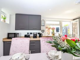 A kitchen with a table set and appliances at Lilly's Cottage in Dawlish