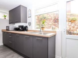A kitchen with cabinets and appliances at Lilly's Cottage Dawlish