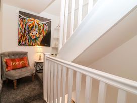 A staircase with wall art and an armchair at Lilly's Cottage in Dawlish