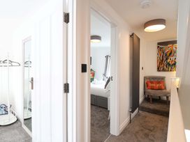 A hallway with a mirror and clothes rack at Lilly's Cottage Dawlish