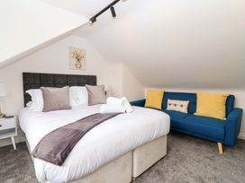 A bedroom with a bed and a blue sofa at Lilly's Cottage in Dawlish
