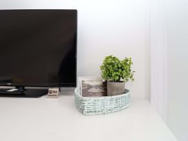 A living room with a television and decorative items at Lilly's Cottage in Dawlish