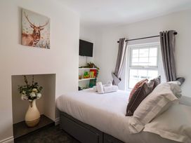 A bedroom with a bed and a vase of flowers at Lilly's Cottage Dawlish