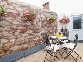 An outdoor patio area with a table and chairs at Lilly's Cottage in Dawlish