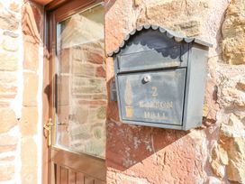 A black mailbox attached to a stone wall next to a wooden door at Rayson Hall Barns in Ousby