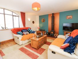 A living room with two sofas a wooden coffee table a wood burning stove and a television at Rayson Hall Barns in Ousby