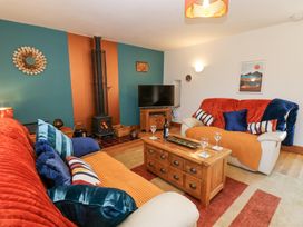 A living room with two sofas a wooden coffee table a television and a wood stove at Rayson Hall Barns in Ousby